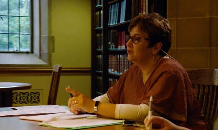 Judith Fox sits at the table, talking with paper in front of her.