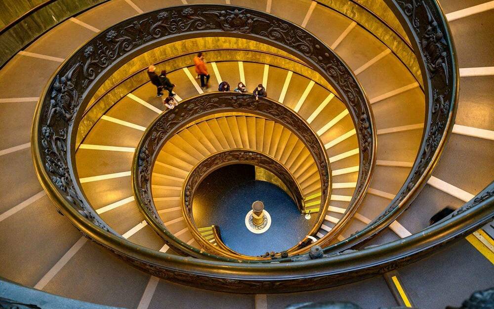 A look down a spiraling, golden-colored staircase.