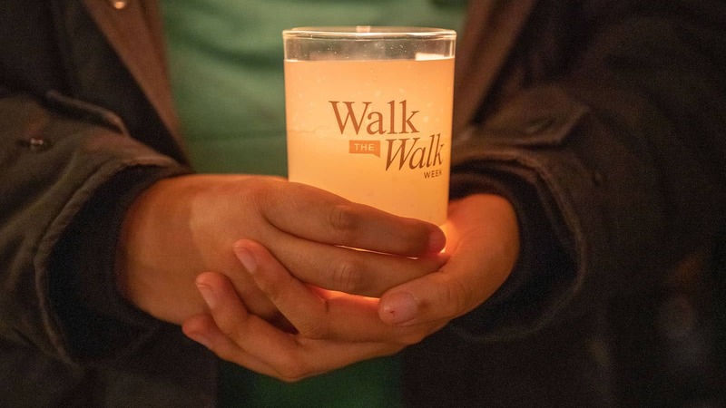 A close up of someone's hands holding a handle with the 'Walk the Walk Week 2022' logo.