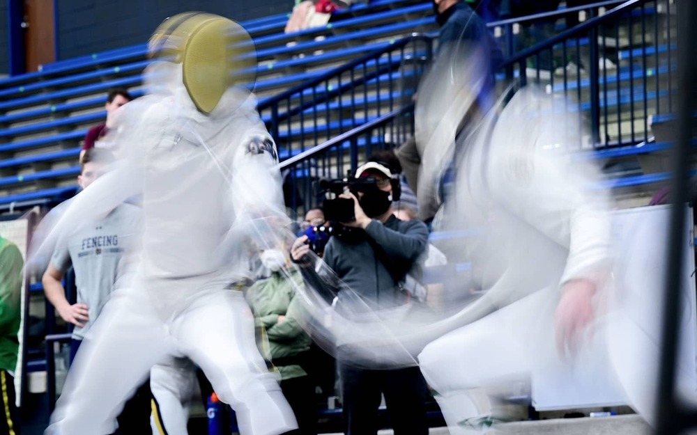 Two fencing figures blurred during action.