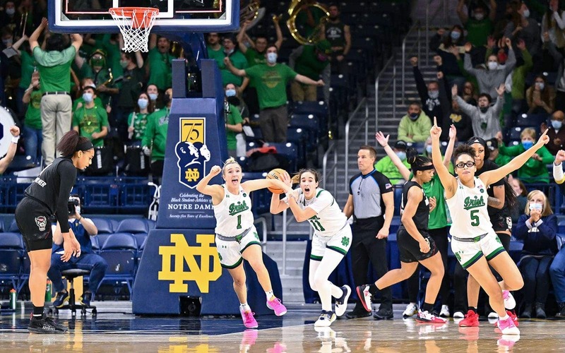 Notre Dame Women's basketball team celebrates on the court.