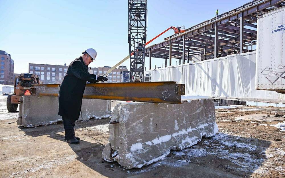 A man signs a metal beam on a construction site.
