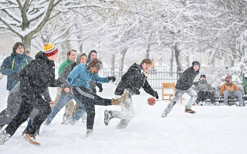 Students play football during a snowstorm.