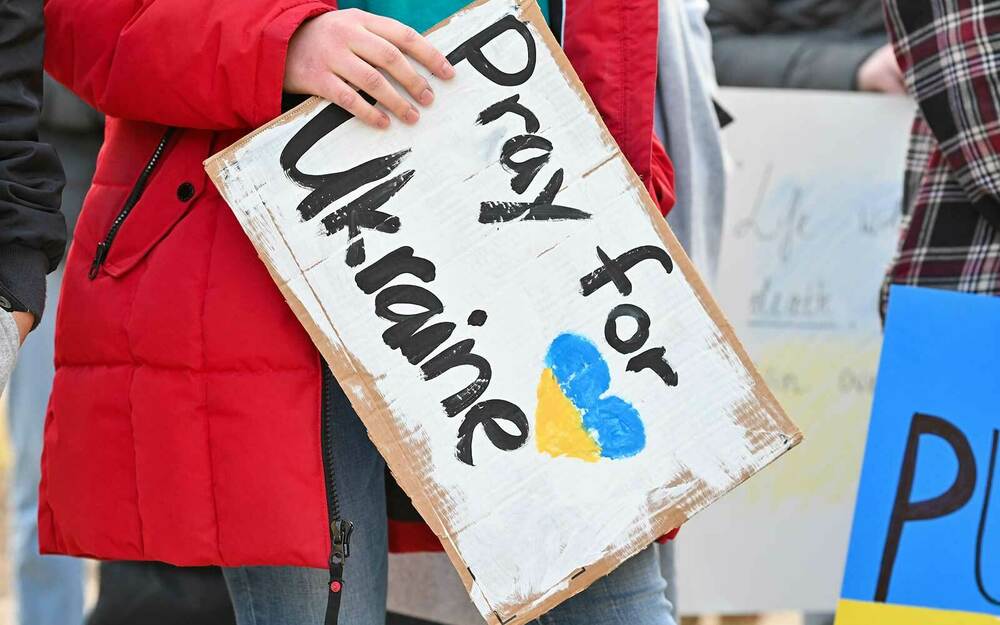 A student holds a sign that says 'Pray for Ukraine'.