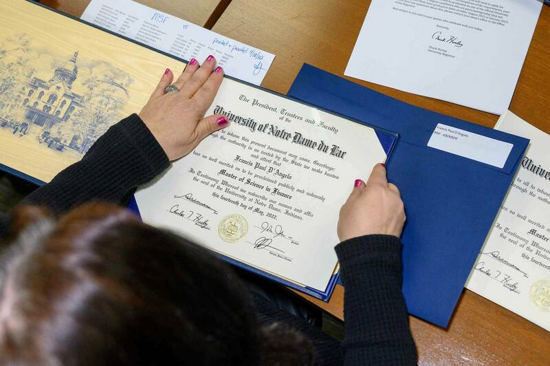 A woman puts a diploma inside of a cover.