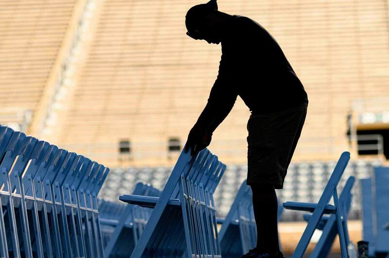 A silhouette of a man places rows of chairs.