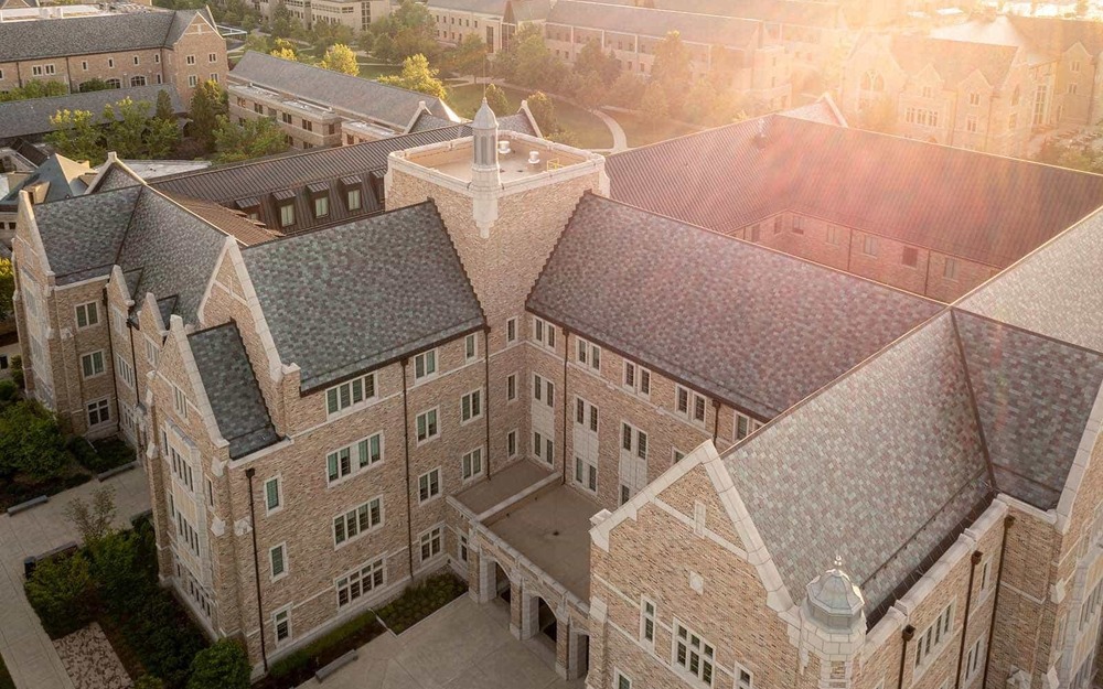 An aerial photo of a large campus building with a sunburst in the right top corner.