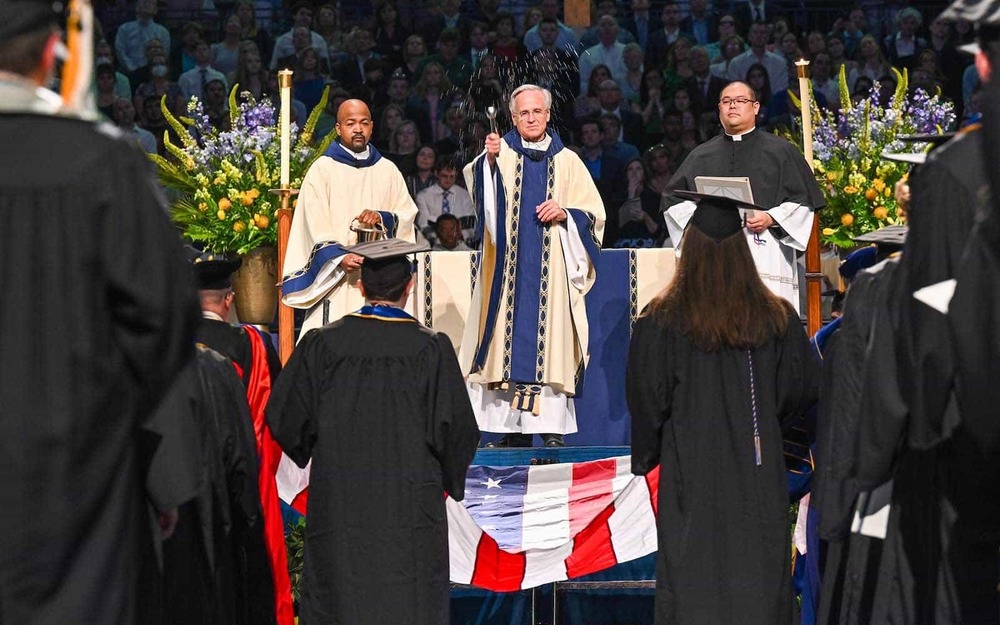 Notre Dame President Rev. John I. Jenkins, C.S.C. blesses a U.S. flag at the end of the 2022 Commencement Mass.