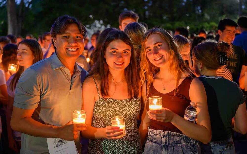 Graduating seniors during Senior Week 2022 pose for a photo holding candles.