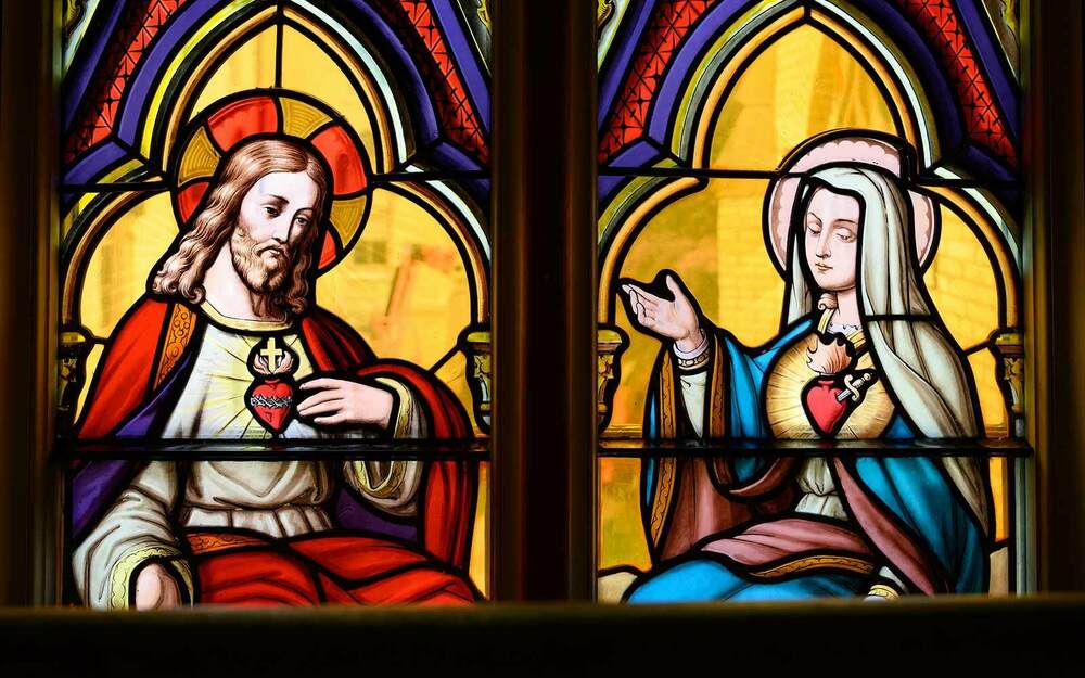 The statue of the Virgin Mary atop the Golden Dome at the University of Notre Dame can be seen through a stained glass window in the Basilica of the Sacred Heart depicting the Virgin Mary and Jesus.
