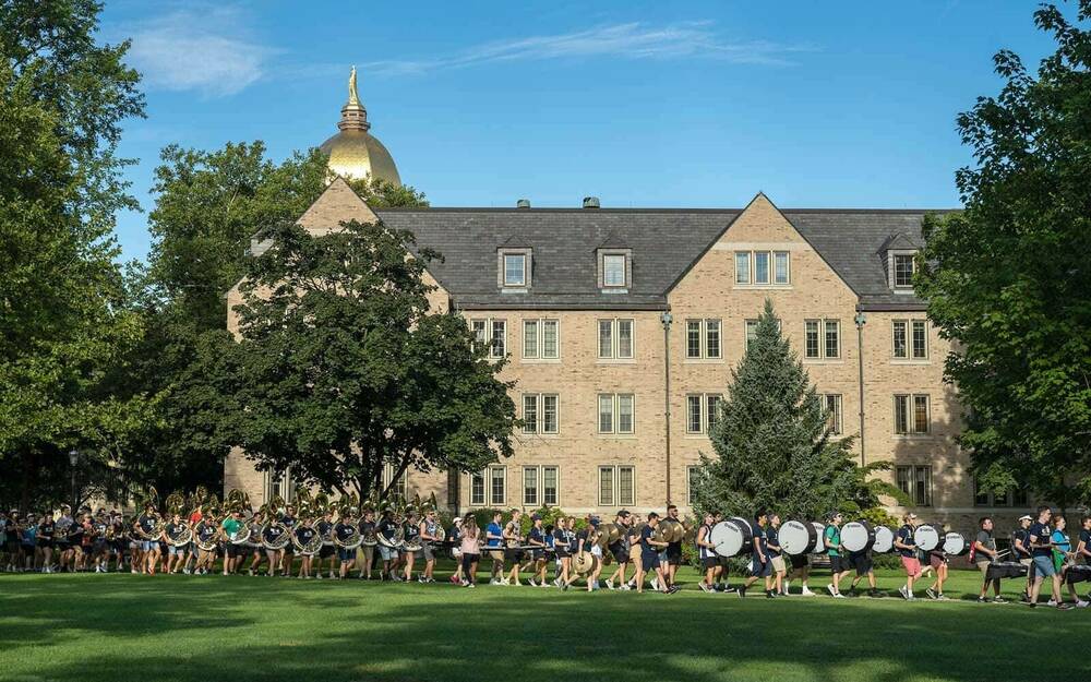 A marching band walks through Notre Dame's campus.