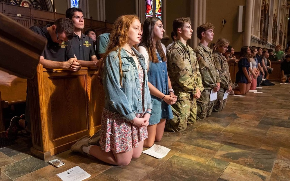 Students kneel in the Basilica of the Sacred Heart.