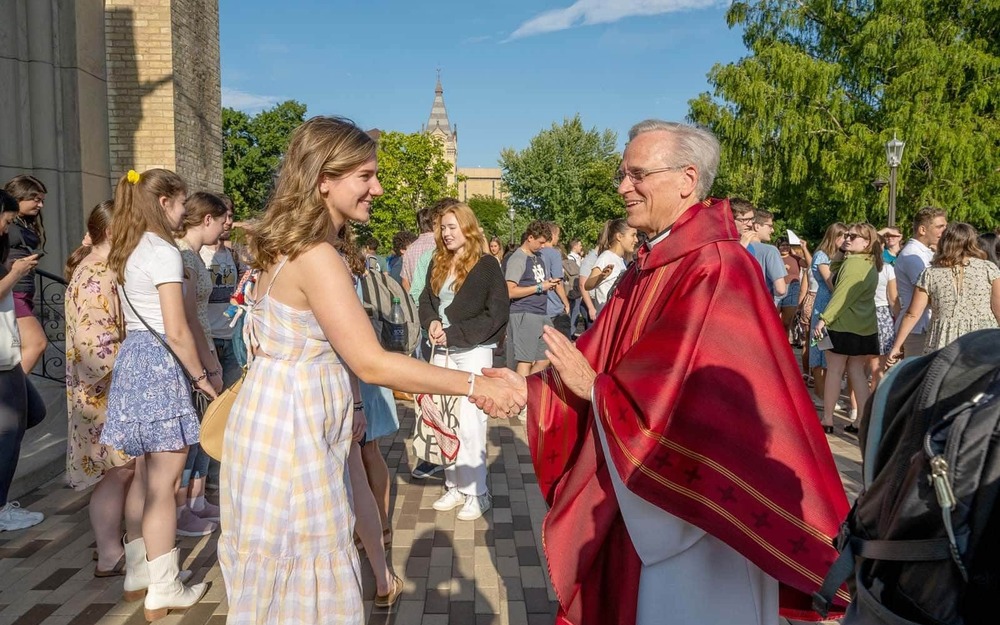 A female student shakes hands with University of Notre Dame President Rev. John I. Jenkins, C.S.C.