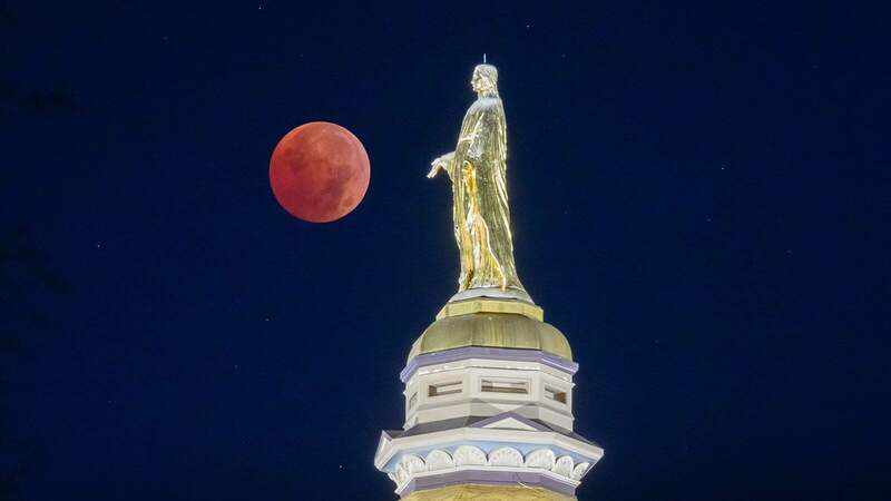 Mary from atop of the golden dome at night facing the blood moon