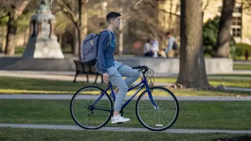 A male student riding his bike across campus