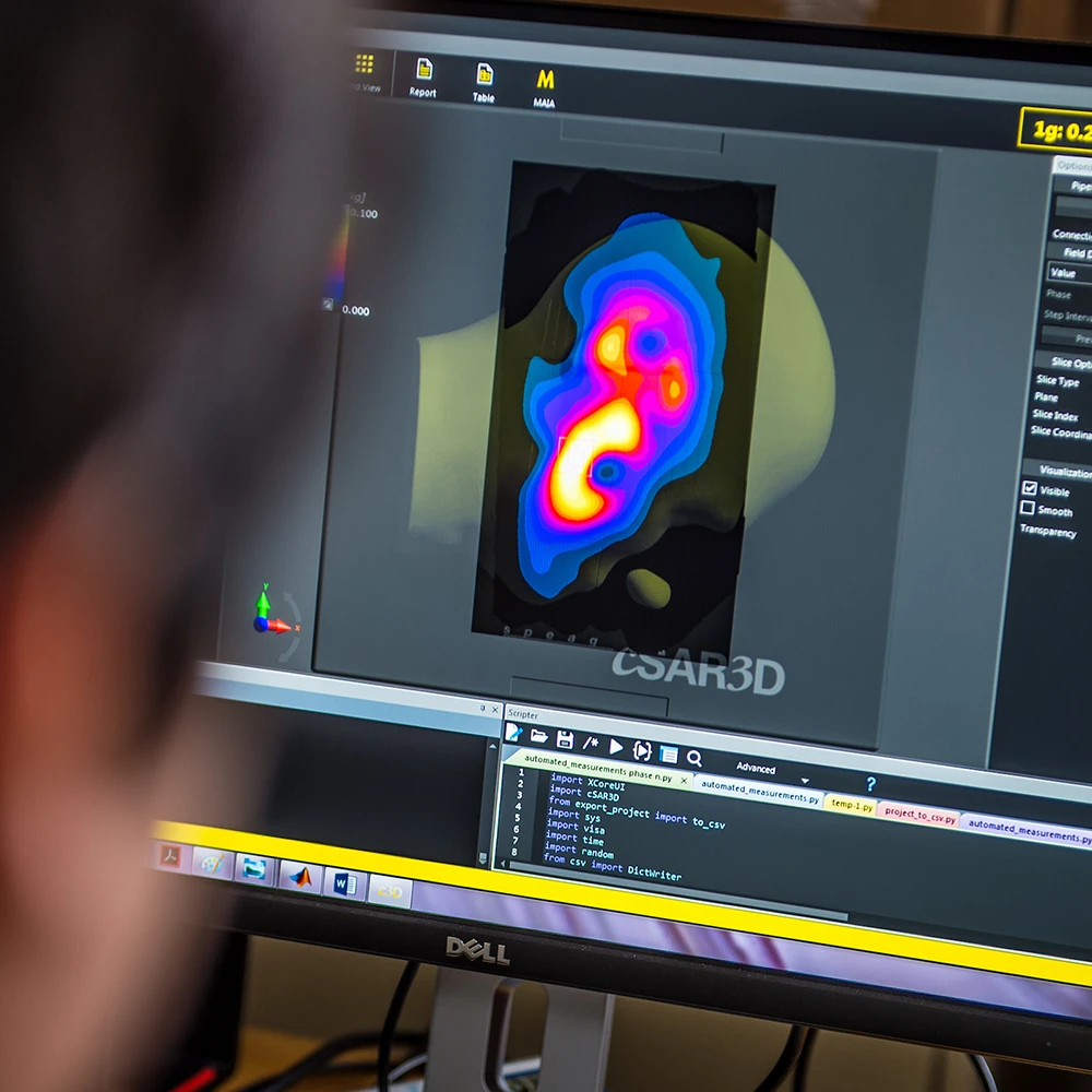 A person looks at a computer screen displaying a colorful heat map of a head and lines of code in a terminal window.